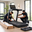 Two professional technicians assembling a treadmill in a bright home gym for out-of-box installation