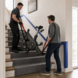 Technician and customer safely carrying an exercise bike upstairs with moving straps