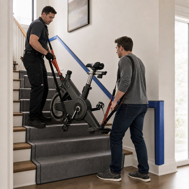 Technician and customer safely carrying an exercise bike upstairs with moving straps